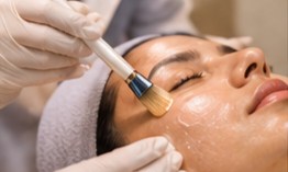 A mask being brushed onto a client's face during a facial